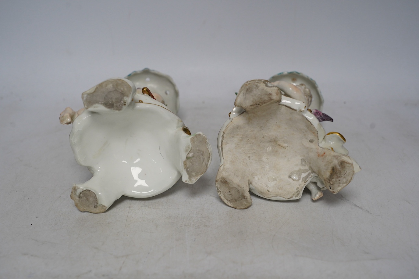 A pair of 19th century Derby porcelain candlesticks, with ‘winged cupid’ stems, 22cm. Condition - poor